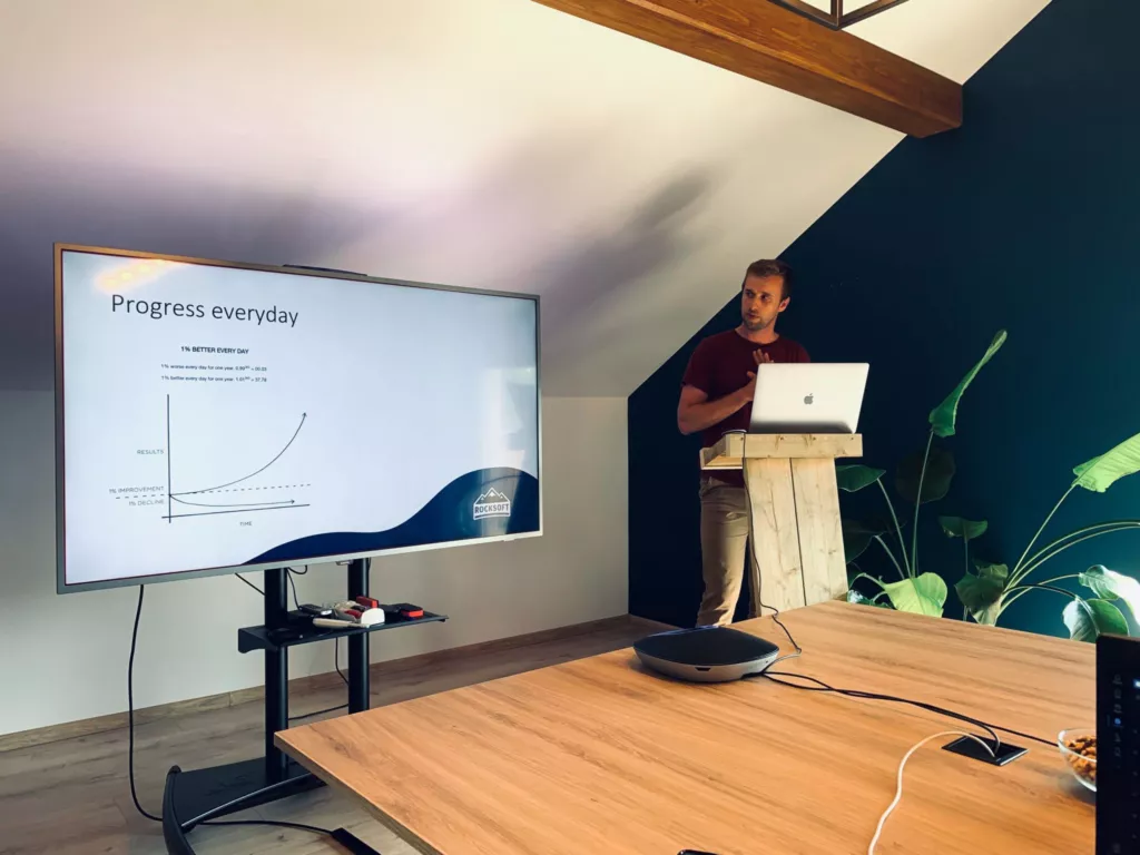 Man standing by a slide of presentation, explaining something