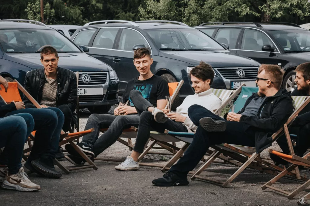 A group of men sitting in foldable chairs, chatting and smiling