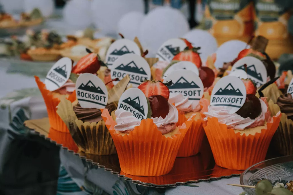 Cupcakes decorated with the Rocksoft logo and topped with fresh strawberries